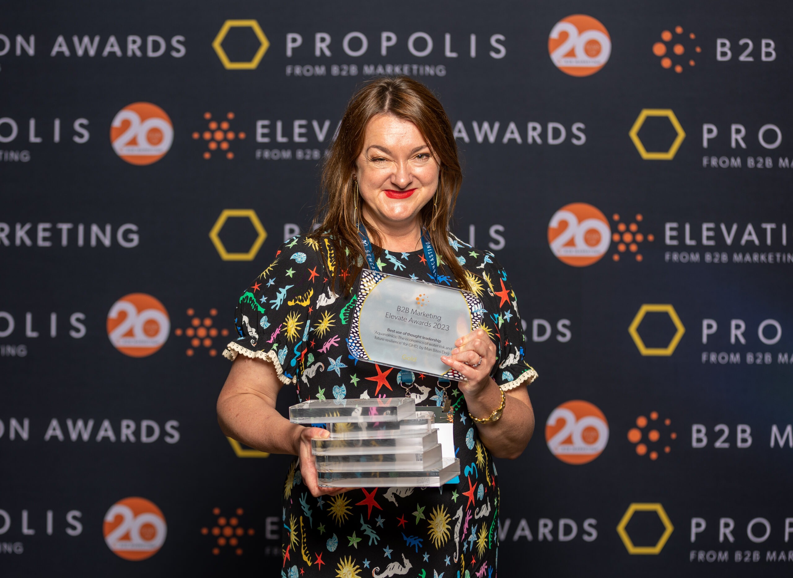 Claire Mason, Man Bites Dog Founder and CEO, holding six trophies at the 2023 Elevation Awards