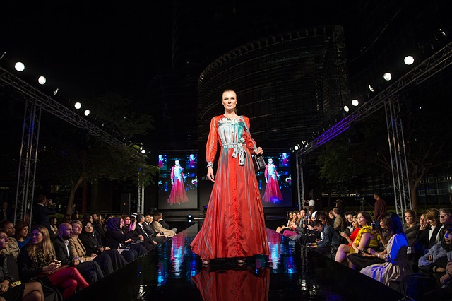 A woman walks down a catwalk in front of an audience